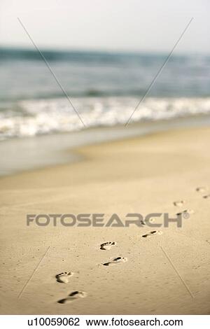 Stock Image - Scenic sandy coastline with footprints and waves.. Fotosearch