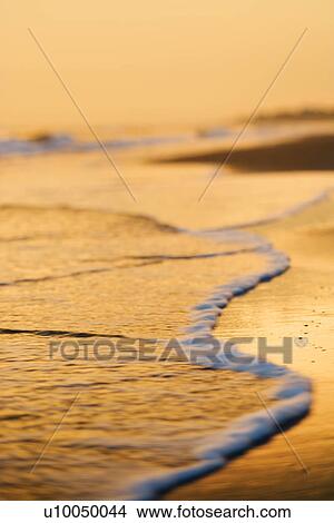 Waves lapping on beach at sunset. View Large Photo Image Picture - Waves lapping on beach at sunset.. Fotosearch