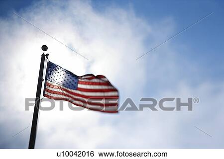 American flag blowing in breeze against blue sky. View Large Photo Image Stock Photograph - American flag blowing in breeze against blue sky.. Fotosearch