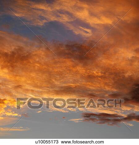 Stock Image - Orange clouds in sky with sunset.. Fotosearch