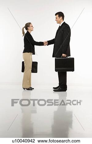 Caucasian mid-adult businessman and woman shaking hands and holding briefcases. View Large Photo Image Stock Image - Caucasian mid-adult businessman and woman shaking hands and holding briefcases.. Fotosearch