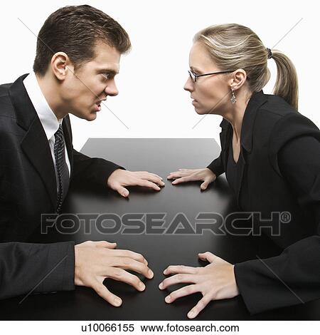 Stock Photography - Caucasian mid-adult businessman and woman staring at each other with hostile expression.. Fotosearch