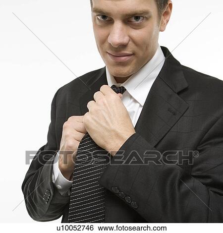 Stock Photograph - Caucasian mid-adult man straightening necktie.. Fotosearch