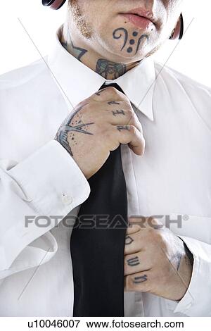 Stock Photo - Caucasian mid-adult man with tattoos and piercings adjusting necktie.. Fotosearch