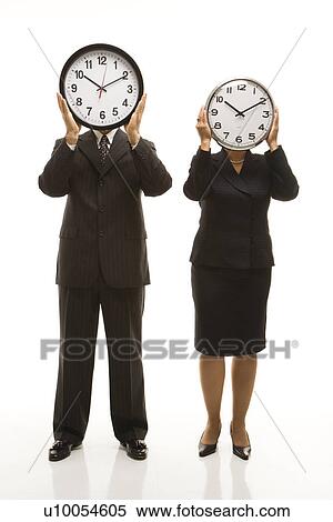 Caucasian middle-aged businessman and Filipino businesswoman holding clocks in front of their heads standing against white background. View Large Photo Image Stock Photography - Caucasian middle-aged businessman and Filipino businesswoman holding clocks in front of their heads standing against white background.. Fotosearch