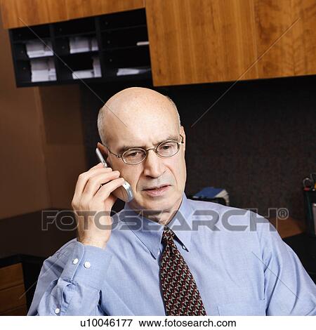 Caucasian middle-aged businessman sitting in office talking on cellphone. View Large Photo Image Stock Photo - Caucasian middle-aged businessman sitting in office talking on cellphone.. Fotosearch