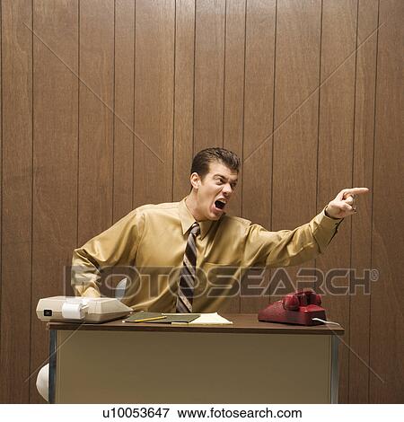 Caucasion mid-adult retro businessman sitting at desk pointing in anger. View Large Photo Image Stock Photo - Caucasion mid-adult retro businessman sitting at desk pointing in anger.. Fotosearch