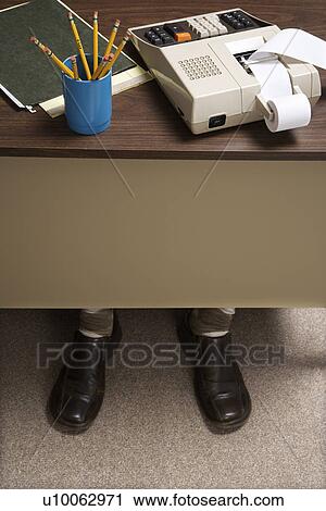 Feet of retro businessman sticking out of bottom of desk with notebook, pencils and adding machine. View Large Photo Image Stock Image - Feet of retro businessman sticking out of bottom of desk with notebook, pencils and adding machine.. Fotosearch