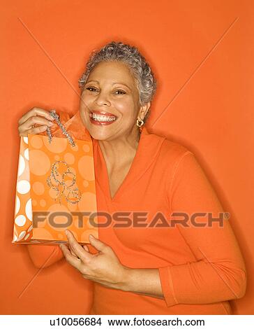 African American mature adult female holding gift bag. View Large Photo Image Picture - African American mature adult female holding gift bag.. Fotosearch