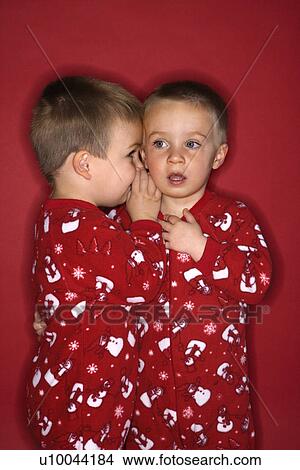 Picture - Young male twin child whispering to other twin.. Fotosearch