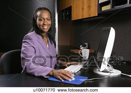African-American young adult business woman working at computer in office smiling and looking at viewer. View Large Photo Image Stock Image - African-American young adult business woman working at computer in office smiling and looking at viewer.. Fotosearch