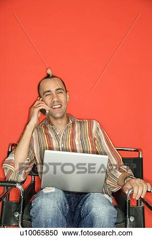 Caucasian man with mohawk holding laptop talking on cellphone against red background. View Large Photo Image Stock Image - Caucasian man with mohawk holding laptop talking on cellphone against red background.. Fotosearch