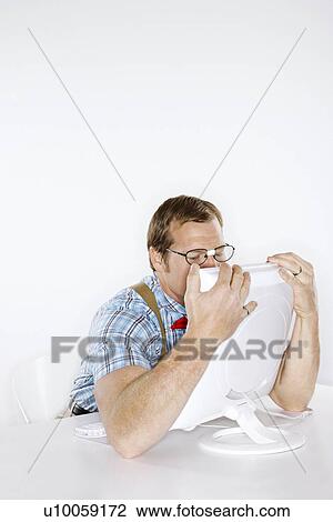 Stock Image - Caucasian young man dressed like nerd embracing computer with face pressed to monitor.. Fotosearch