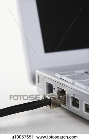 Stock Image - Data wire connected to laptop computer.. Fotosearch