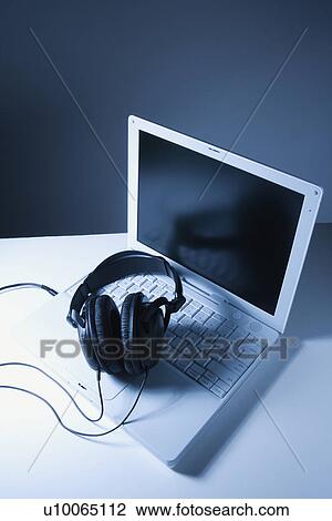 Stock Image - Headphones placed on laptop computer.. Fotosearch