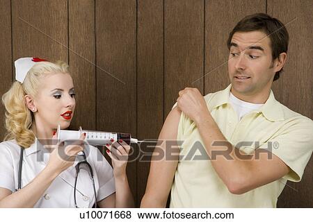Stock Photo - Caucasian mid-adult female nurse giving shot to man with oversized syringe.. Fotosearch