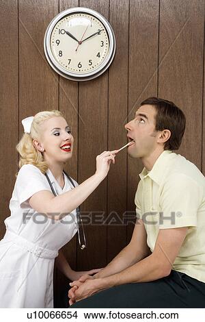 Picture - Caucasian mid-adult female nurse examinating male's mouth with tongue depressor.. Fotosearch