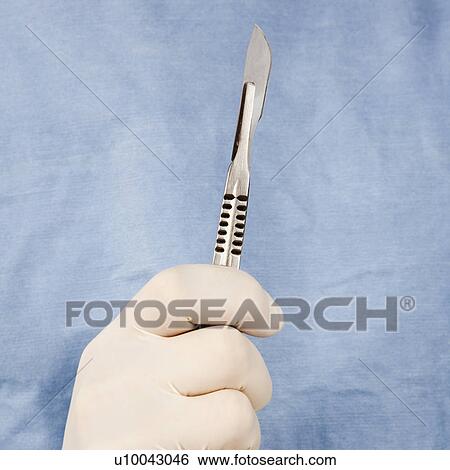 Stock Photograph - Close-up of male surgeon's gloved hand holding scalpel.. Fotosearch