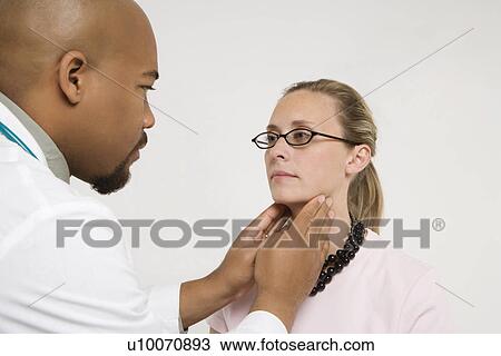 Mid-adult African-American doctor examining Caucasion mid-adult female patient. View Large Photo Image Stock Image - Mid-adult African-American doctor examining Caucasion mid-adult female patient.. Fotosearch