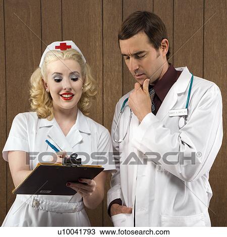 Mid-adult Caucasian female nurse and male doctor standing looking at clipboard. View Large Photo Image Stock Image - Mid-adult Caucasian female nurse and male doctor standing looking at clipboard.. Fotosearch