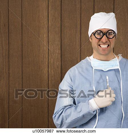 Stock Photo - Mid-adult Caucasian male surgeon wearing thick glasses and holding scalpel smiling maniacally.. Fotosearch