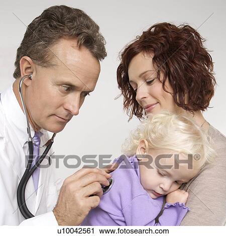 Middle-aged adult Caucasian male doctor holding stethoscope to female toddler's back with mother watching. View Large Photo Image Stock Image - Middle-aged adult Caucasian male doctor holding stethoscope to female toddler's back with mother watching.. Fotosearch