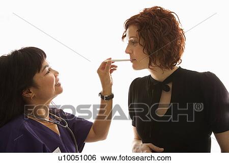 Nurse putting tongue depressor into Caucasian pregnant woman's mouth. View Large Photo Image Stock Photograph - Nurse putting tongue depressor into Caucasian pregnant woman's mouth.. Fotosearch
