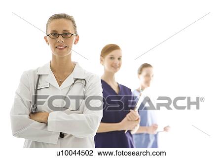 Stock Image - Portrait of smiling Caucasian medical healthcare workers in uniforms standing against white background.. Fotosearch