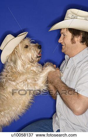 Fluffy brown dog and male Caucasian young adult wearing cowboy hats. View Large Photo Image Stock Photo - Fluffy brown dog and male Caucasian young adult wearing cowboy hats.. Fotosearch