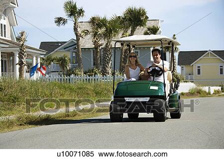 Caucasian mid-adult man and woman driving golf cart down residential street. View Large Photo Image Stock Photography - Caucasian mid-adult man and woman driving golf cart down residential street.. Fotosearch