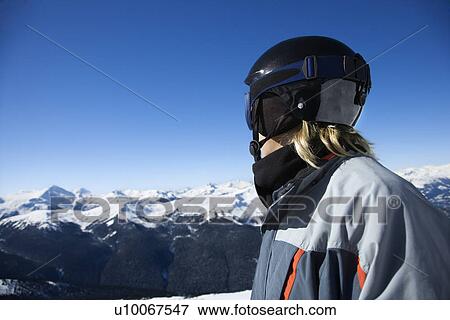 Stock Photo - Caucasian teenage boy snowboarder wearing helmet and goggles on mountain.. Fotosearch