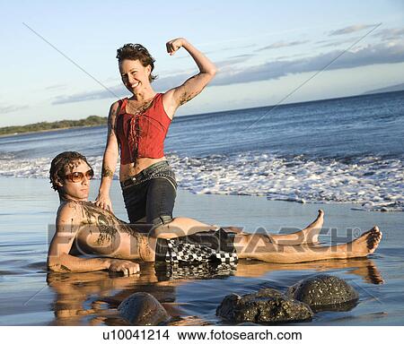 Picture - Caucasian young adult couple frolicking on beach.. Fotosearch