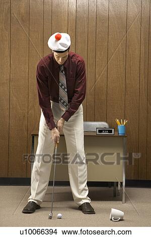 Caucasion mid-adult retro businessman wearing cap putting golf ball into coffee cup in his office. View Large Photo Image Picture - Caucasion mid-adult retro businessman wearing cap putting golf ball into coffee cup in his office.. Fotosearch