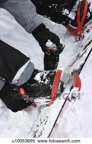 Stock Photography - Person strapping on snowboard.. Fotosearch