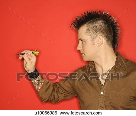 Side view of Caucasian man with mohawk holding dart against red background. View Large Photo Image Stock Photograph - Side view of Caucasian man with mohawk holding dart against red background.. Fotosearch
