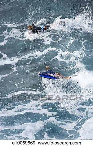 Two adolescent Caucasian males riding boogie boards on wave in Maui. View Large Photo Image Stock Photo - Two adolescent Caucasian males riding boogie boards on wave in Maui.. Fotosearch