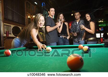 Stock Photograph - Young asian woman preparing to hit pool ball while playing billiards.. Fotosearch