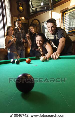 Stock Image - Young caucasian woman receiving advice on shooting pool ball while playing billiards.. Fotosearch