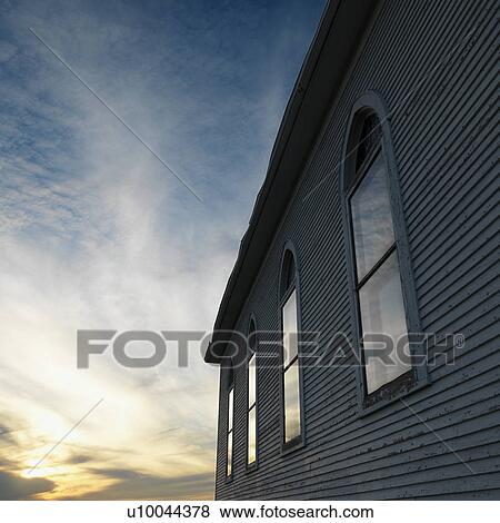 Sunset and clouds behind side view of building with arched windows and wooden siding. View Large Photo Image Stock Photo - Sunset and clouds behind side view of building with arched windows and wooden siding.. Fotosearch