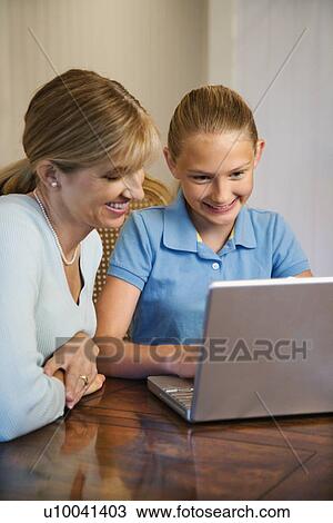 Stock Image - Caucasian mid-adult woman and pre-teen girl using laptop computer.. Fotosearch