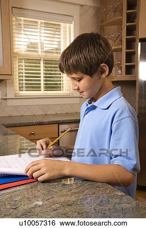 Stock Photograph - Caucasian pre-teen boy doing homework at kitchen counter.. Fotosearch