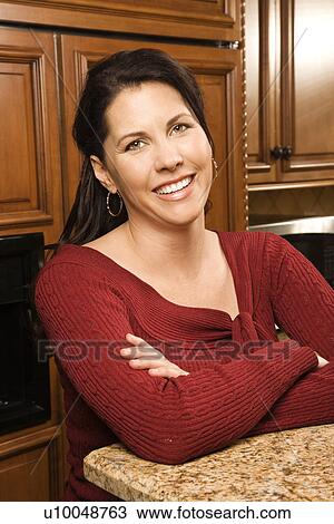 Caucasian woman in kitchen smiling and looking at viewer. View Large Photo Image Stock Image - Caucasian woman in kitchen smiling and looking at viewer.. Fotosearch