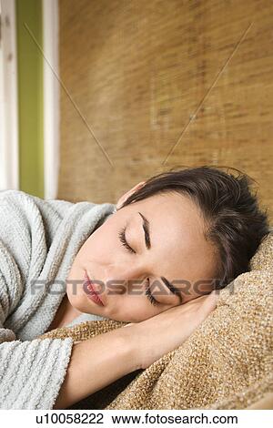 Stock Image - Caucasian/Hispanic young woman with eyes closed laying down.. Fotosearch