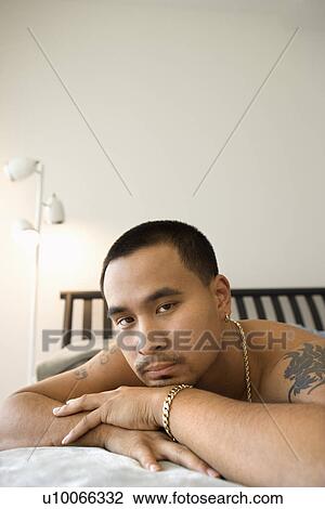 Close-up of shirtless Asian young adult man looking at viewer with head resting on arms. View Large Photo Image Stock Image - Close-up of shirtless Asian young adult man looking at viewer with head resting on arms.. Fotosearch