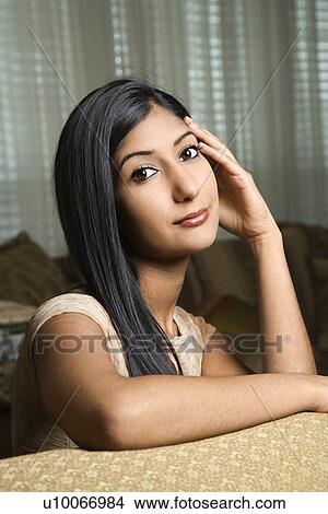 Close up portrait of Asian/Indian young woman sitting on couch. View Large Photo Image Picture - Close up portrait of Asian/Indian young woman sitting on couch.. Fotosearch