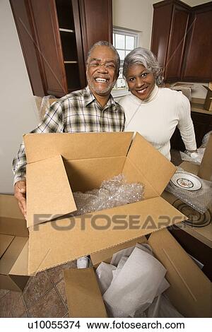 Portrait of middle-aged African-American couple with moving boxes in kitchen. View Large Photo Image Picture - Portrait of middle-aged African-American couple with moving boxes in kitchen.. Fotosearch