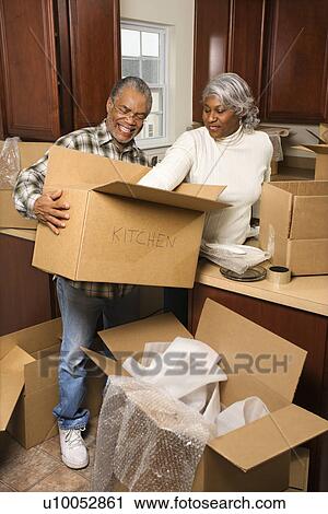 Portrait of middle-aged African-American couple packing moving boxes in kitchen. View Large Photo Image Stock Image - Portrait of middle-aged African-American couple packing moving boxes in kitchen.. Fotosearch