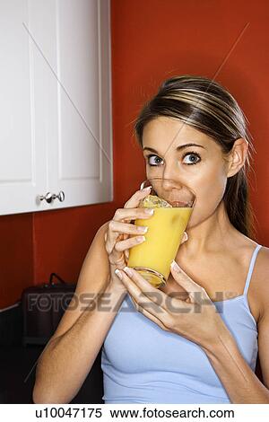 Portrait of young adult woman drinking a glass of orange juice. View Large Photo Image Stock Photography - Portrait of young adult woman drinking a glass of orange juice.. Fotosearch