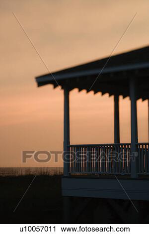 Stock Image - Beachfront porch silhouetted at sunset. Fotosearch