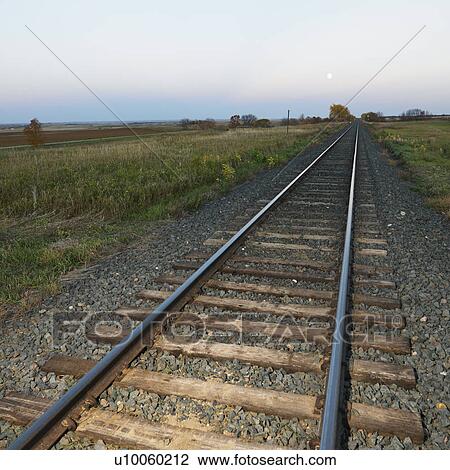 Low angle diminishing view of railroad tracks in rural setting at dusk. View Large Photo Image Stock Image - Low angle diminishing view of railroad tracks in rural setting at dusk.. Fotosearch